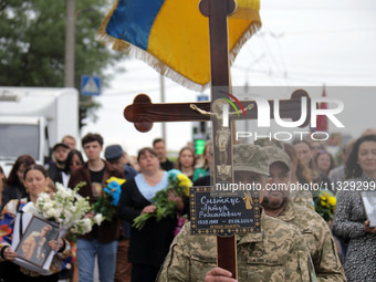 A soldier is carrying the cross as the funeral procession of Ukrainian serviceman, artist, musician, stylist, and queer community member Art...