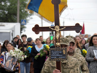 A soldier is carrying the cross as the funeral procession of Ukrainian serviceman, artist, musician, stylist, and queer community member Art...