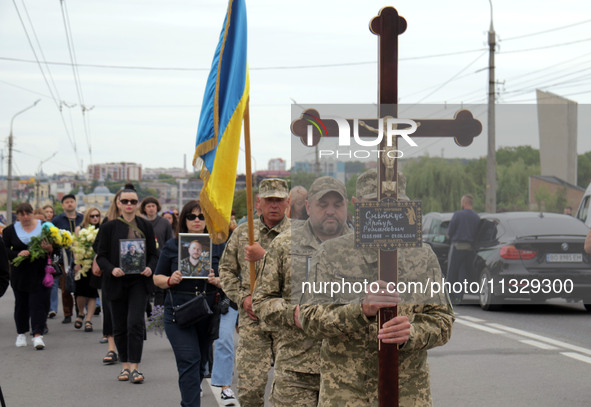 A soldier is carrying the cross as the funeral procession of Ukrainian serviceman, artist, musician, stylist, and queer community member Art...