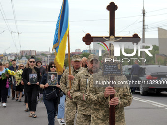 A soldier is carrying the cross as the funeral procession of Ukrainian serviceman, artist, musician, stylist, and queer community member Art...