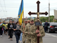 A soldier is carrying the cross as the funeral procession of Ukrainian serviceman, artist, musician, stylist, and queer community member Art...