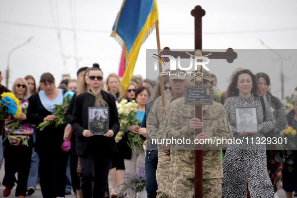 A soldier is carrying the cross as the funeral procession of Ukrainian serviceman, artist, musician, stylist, and queer community member Art...