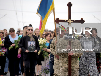 A soldier is carrying the cross as the funeral procession of Ukrainian serviceman, artist, musician, stylist, and queer community member Art...