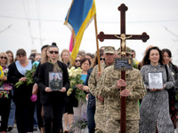 A soldier is carrying the cross as the funeral procession of Ukrainian serviceman, artist, musician, stylist, and queer community member Art...