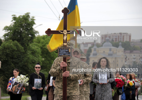 A soldier is carrying the cross as the funeral procession of Ukrainian serviceman, artist, musician, stylist, and queer community member Art...