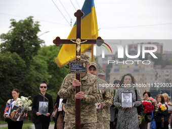 A soldier is carrying the cross as the funeral procession of Ukrainian serviceman, artist, musician, stylist, and queer community member Art...