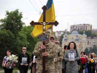 A soldier is carrying the cross as the funeral procession of Ukrainian serviceman, artist, musician, stylist, and queer community member Art...