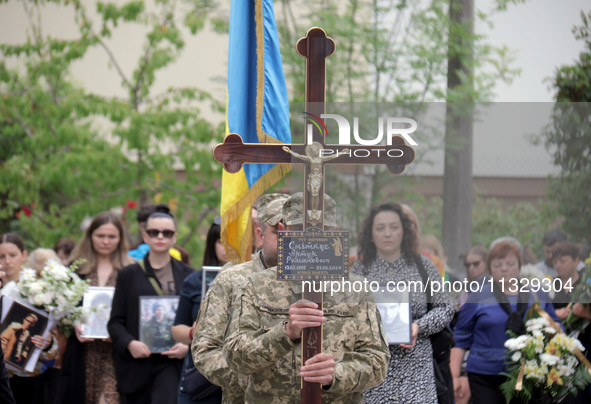 A soldier is carrying the cross as the funeral procession of Ukrainian serviceman, artist, musician, stylist, and queer community member Art...