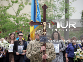 A soldier is carrying the cross as the funeral procession of Ukrainian serviceman, artist, musician, stylist, and queer community member Art...