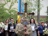 A soldier is carrying the cross as the funeral procession of Ukrainian serviceman, artist, musician, stylist, and queer community member Art...