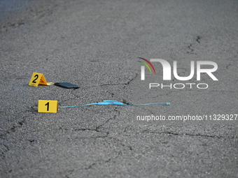 Evidence markers are showing a USB charger and a phone on the ground at the mass shooting crime scene. Four people are being shot in a mass...