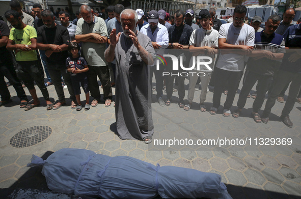 Mourners are praying by the body of Muhammad Abu Aisha, who is dying following the Israeli bombardment of a residential apartment in Deir al...