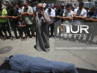 Mourners are praying by the body of Muhammad Abu Aisha, who is dying following the Israeli bombardment of a residential apartment in Deir al...