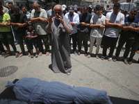 Mourners are praying by the body of Muhammad Abu Aisha, who is dying following the Israeli bombardment of a residential apartment in Deir al...