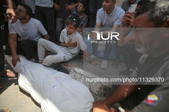 Mourners are praying by the body of Muhammad Abu Aisha, who is dying following the Israeli bombardment of a residential apartment in Deir al...