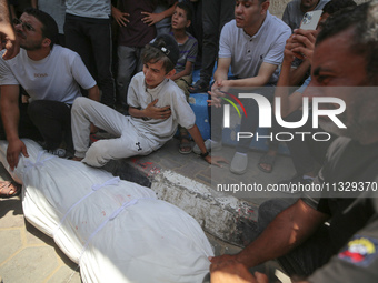 Mourners are praying by the body of Muhammad Abu Aisha, who is dying following the Israeli bombardment of a residential apartment in Deir al...