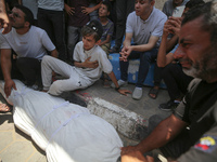 Mourners are praying by the body of Muhammad Abu Aisha, who is dying following the Israeli bombardment of a residential apartment in Deir al...