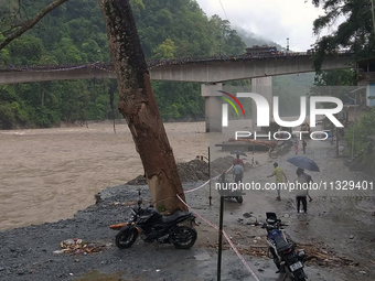 Villagers are walking on the roads adjacent to the Teesta River, where water is entering the roads near their houses due to the risen water...