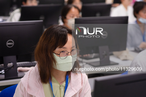 A marking teacher is carefully evaluating a college entrance examination paper at a marking point at a college in Nanjing, China, on June 14...