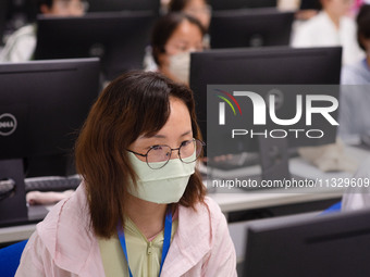 A marking teacher is carefully evaluating a college entrance examination paper at a marking point at a college in Nanjing, China, on June 14...