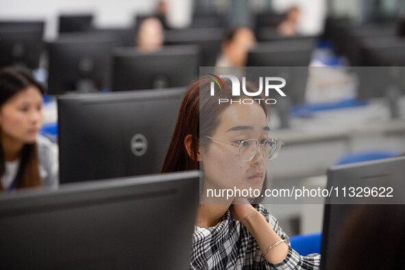 A marking teacher is carefully evaluating a college entrance examination paper at a marking point at a college in Nanjing, China, on June 14...