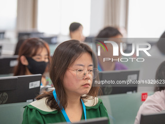 A marking teacher is carefully evaluating a college entrance examination paper at a marking point at a college in Nanjing, China, on June 14...