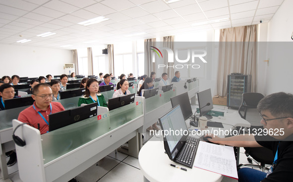 A marking teacher is carefully evaluating a college entrance examination paper at a marking point at a college in Nanjing, China, on June 14...