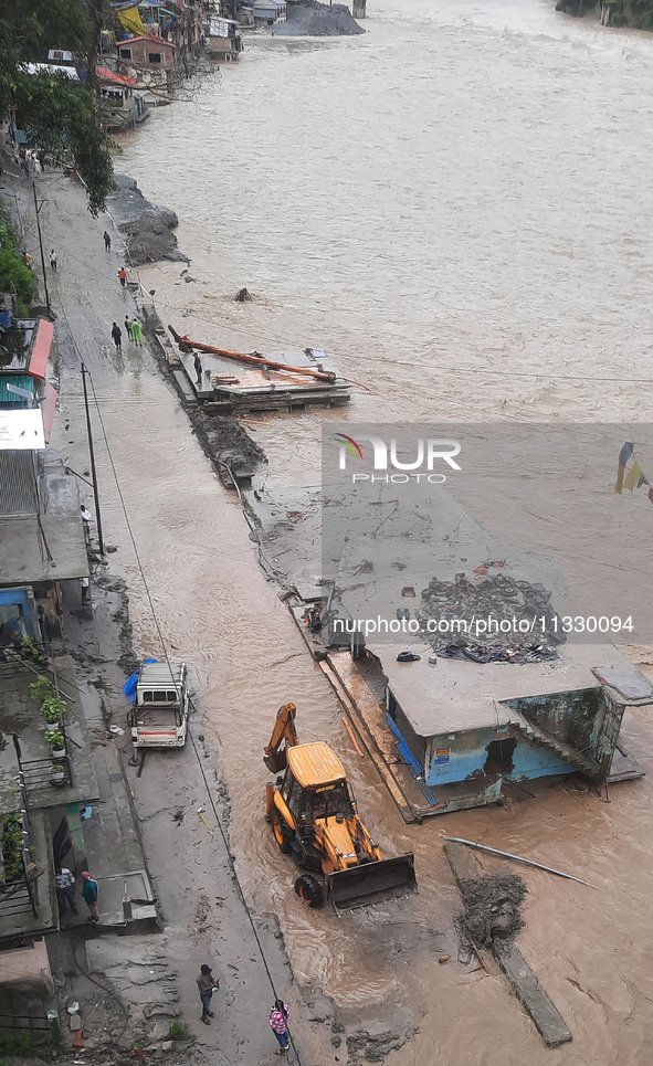 Villagers are walking on the roads adjacent to the Teesta River, where water is entering the roads near their houses due to heavy rain in th...