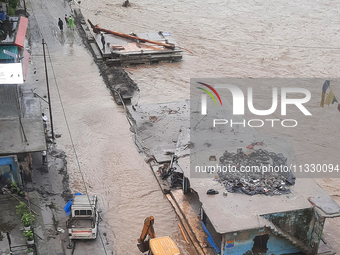 Villagers are walking on the roads adjacent to the Teesta River, where water is entering the roads near their houses due to heavy rain in th...