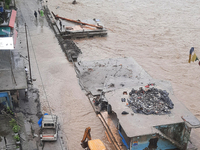 Villagers are walking on the roads adjacent to the Teesta River, where water is entering the roads near their houses due to heavy rain in th...