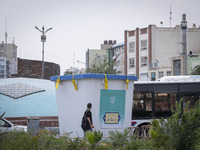 A young Iranian man is walking past a model of a ballot box that is being placed street-side in downtown Tehran, Iran, on June 14, 2024, dur...