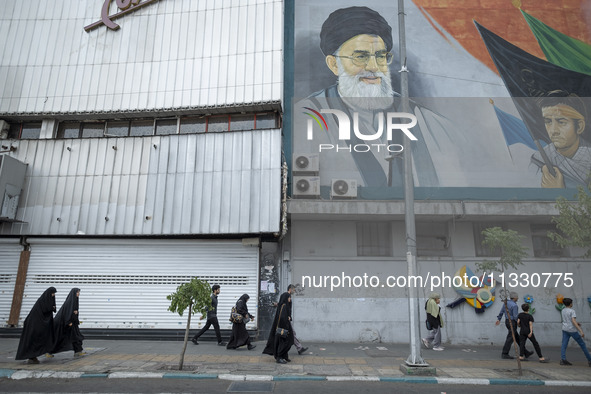 Iranian worshippers are walking along Enghelab (Revolution) Avenue, passing a mural featuring a portrait of Iran's Supreme Leader, Ayatollah...