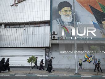 Iranian worshippers are walking along Enghelab (Revolution) Avenue, passing a mural featuring a portrait of Iran's Supreme Leader, Ayatollah...