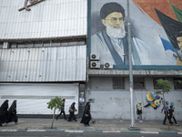 Iranian worshippers are walking along Enghelab (Revolution) Avenue, passing a mural featuring a portrait of Iran's Supreme Leader, Ayatollah...