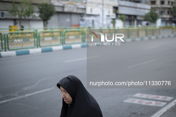 A veiled Iranian worshipper is walking along Enghelab (Revolution) Avenue, as she is making her way to the University of Tehran for Friday p...