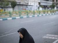 A veiled Iranian worshipper is walking along Enghelab (Revolution) Avenue, as she is making her way to the University of Tehran for Friday p...