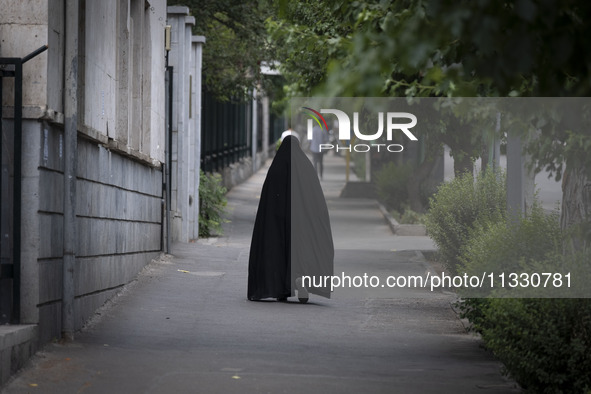 A veiled Iranian worshipper is walking along a sidewalk, making her way to the University of Tehran for Friday prayers ceremonies, amidst th...