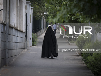 A veiled Iranian worshipper is walking along a sidewalk, making her way to the University of Tehran for Friday prayers ceremonies, amidst th...