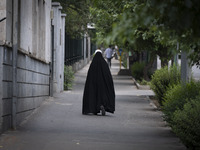 A veiled Iranian worshipper is walking along a sidewalk, making her way to the University of Tehran for Friday prayers ceremonies, amidst th...