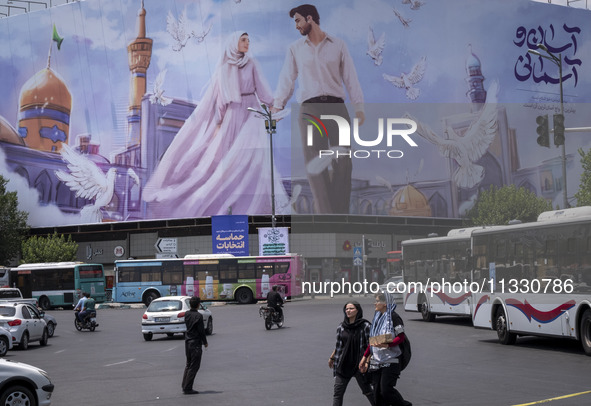 Two young Iranian women are passing an avenue in downtown Tehran, Iran, on June 14, 2024, during Iran's early presidential election campaign...