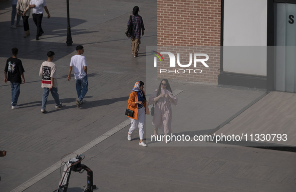 Iranian youths are walking along a recreation area in western Tehran, Iran, on June 14, 2024, amidst the early presidential election campaig...