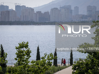 Two Iranian women are walking along a recreation area in western Tehran, Iran, on June 14, 2024, amidst the early presidential election camp...