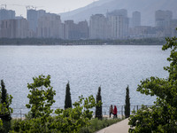 Two Iranian women are walking along a recreation area in western Tehran, Iran, on June 14, 2024, amidst the early presidential election camp...