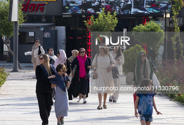 An Iranian family is walking along a recreation area in western Tehran, Iran, on June 14, 2024, amidst the early presidential election campa...