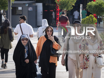 An Iranian family is walking along a recreation area in western Tehran, Iran, on June 14, 2024, amidst the early presidential election campa...