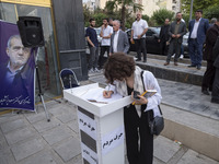 A young Iranian woman, who is not wearing a mandatory headscarf, is writing a note in a notebook dedicated to Masoud Pezeshkian, a reformist...