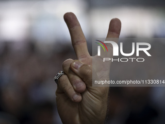 A supporter of Masoud Pezeshkian, Iranian reformist presidential elections candidate, is flashing a Victory sign while taking part in an ele...