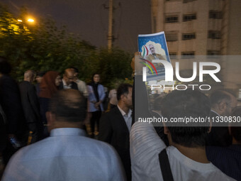 A supporter of Masoud Pezeshkian, an Iranian reformist presidential elections candidate, is holding up an electoral poster featuring a portr...