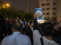 A supporter of Masoud Pezeshkian, an Iranian reformist presidential elections candidate, is holding up an electoral poster featuring a portr...