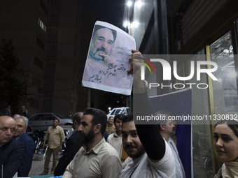 A supporter of Masoud Pezeshkian, an Iranian reformist presidential candidate, is holding up a portrait of former Iranian reformist Presiden...